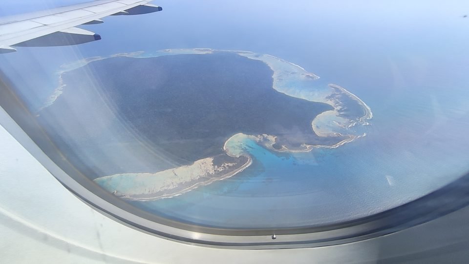 A ilha Sentinela do Norte vista de longe, pela janela de um avião, cercada pelo recife