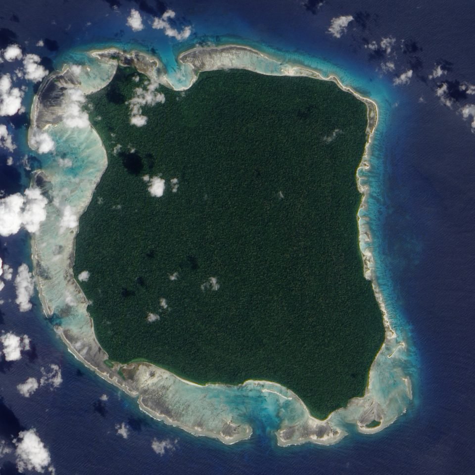 Imagem de satélite da ilha Sentinela do Norte: um quase quadrado de floresta fechada cercado por um anel de recife claro e pelo mar