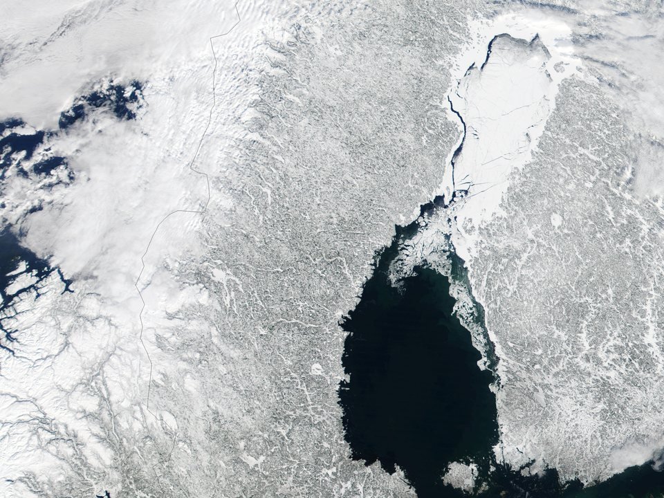 Imagem de satélite do norte da Escandinávia no inverno: terra coberta de neve, a baía de Bótnia congelada no alto e, abaixo, a água escura e aberta do mar de Bótnia
