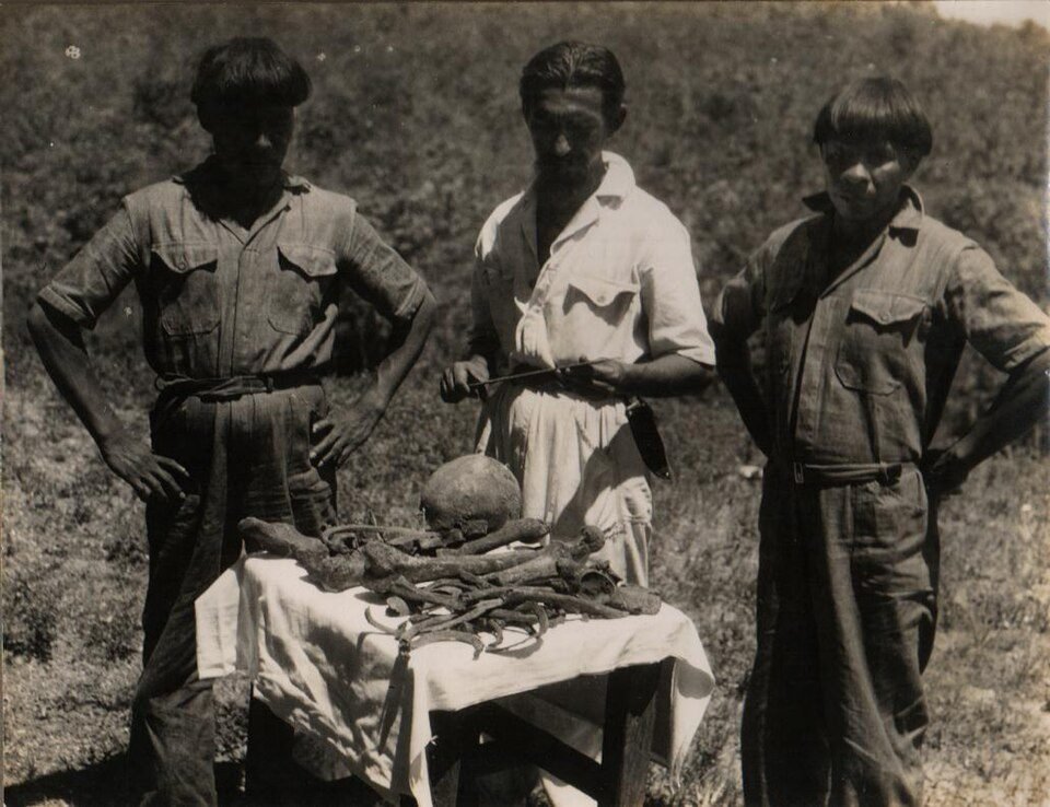 Fotografia de 1952 mostrando Orlando Villas-Bôas e dois homens ao lado de uma mesa com ossos sobre um pano claro