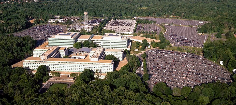 Vista aérea da sede da CIA em Langley: prédios baixos e largos de concreto e vidro cercados de mata, com grandes estacionamentos à direita e ao fundo