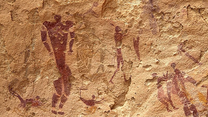 Pintura rupestre de figuras humanas em ocre escuro sobre arenito, uma delas maior e com o corpo decorado