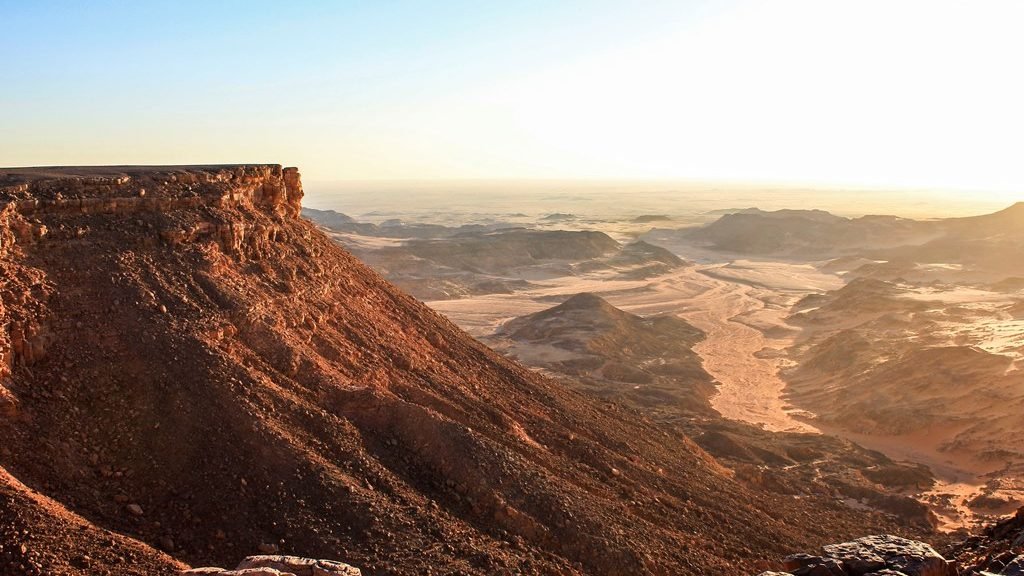 Vista do alto da escarpa do Gilf Kebir olhando para o sul, com o vale do Wadi Sura ao fundo sob luz baixa
